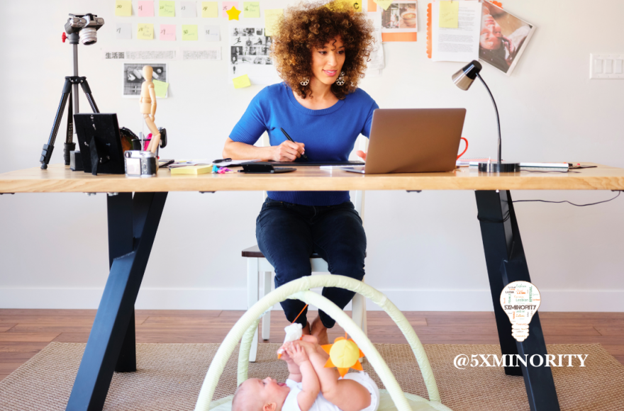 business woman working in front of laptop with newborn playing on the floor near her